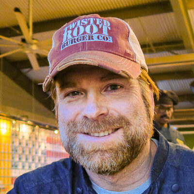 A man in a hat, who is also a Dallas restaurant consultant, smiles for the camera.